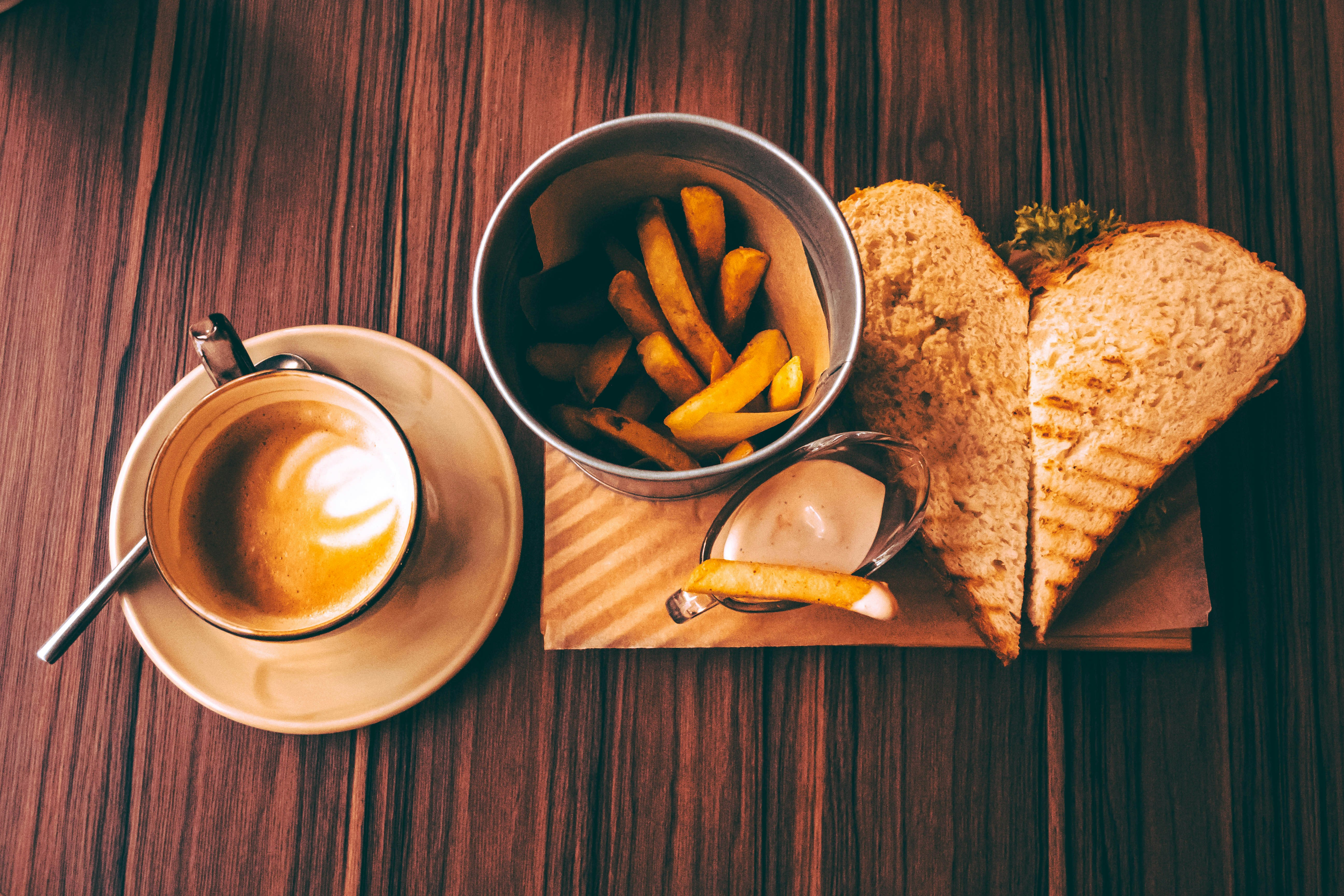 French fries in bucket near sandwich on plate on table